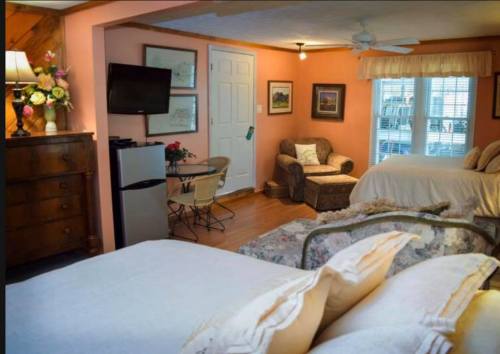 Cozy room with two beds, a small seating area, TV, and a mini fridge, featuring warm peach walls and wooden accents.