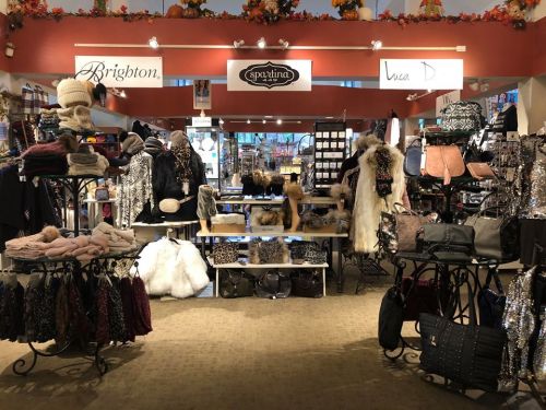 A boutique display featuring various accessories, including hats, bags, and scarves, organized on shelves and tables.