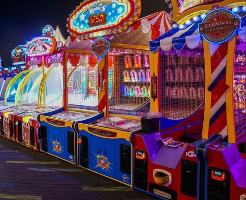 Colorful arcade games with bright lights and carnival-themed decorations in a lively entertainment space.