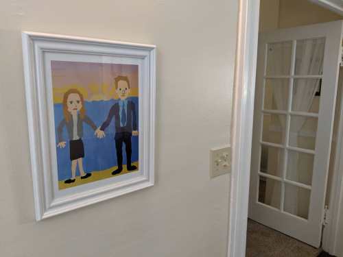 A framed colorful illustration of a couple holding hands, displayed on a wall near a door with glass panels.
