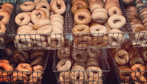 A display of various bagels in wire baskets, showcasing different flavors and textures.