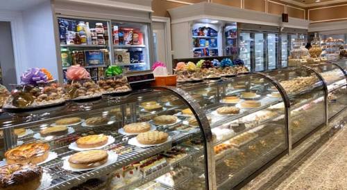 A display case filled with various desserts, including cakes, pastries, and colorful confections.
