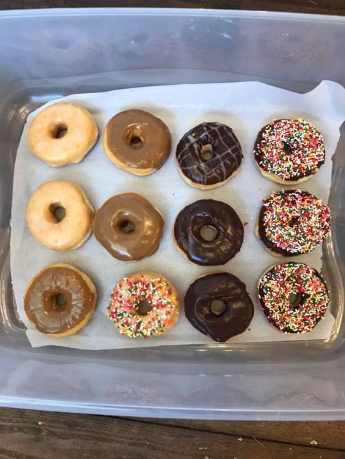 A tray of assorted donuts: plain, chocolate, glazed, and sprinkled, arranged in two rows.