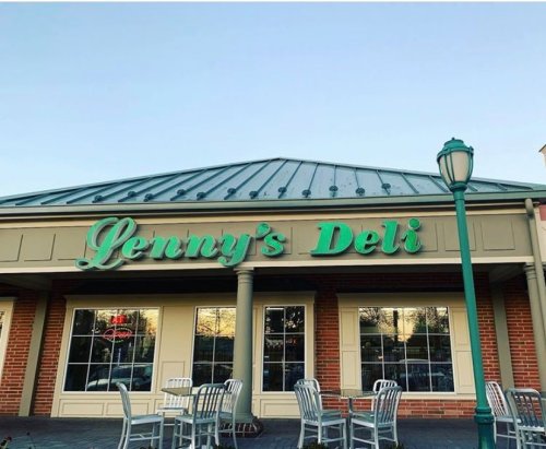 Exterior of Lenny's Deli featuring a green sign, brick walls, and outdoor seating under a clear sky.