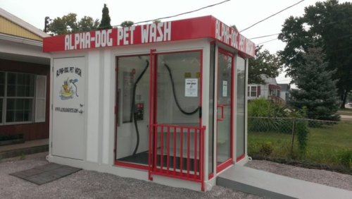 Self-service pet wash station with a red and white exterior, featuring a washing area and signage for "Alpha-Dog Pet Wash."