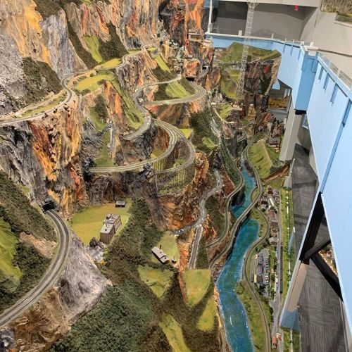A detailed model landscape featuring winding roads, mountains, and a river, showcasing intricate miniature scenery.
