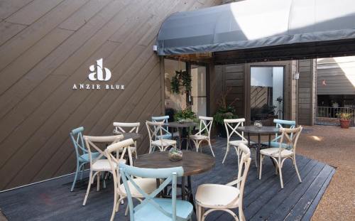 Outdoor seating area with tables and chairs in front of a building featuring the logo "Anzie Blue."