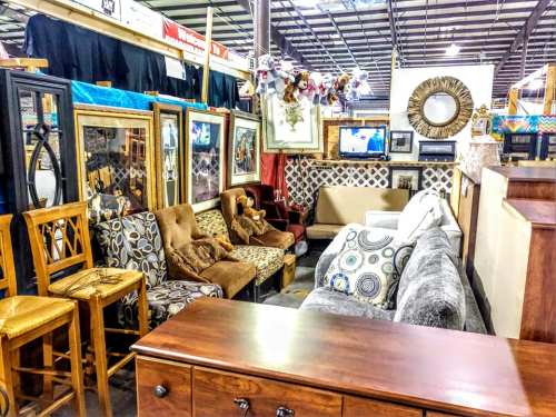 A cozy furniture display featuring various seating options, including chairs and sofas, in a well-lit warehouse setting.