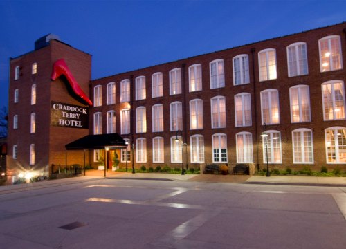 Exterior view of the Craddock Terry Hotel at dusk, featuring brick architecture and illuminated windows.