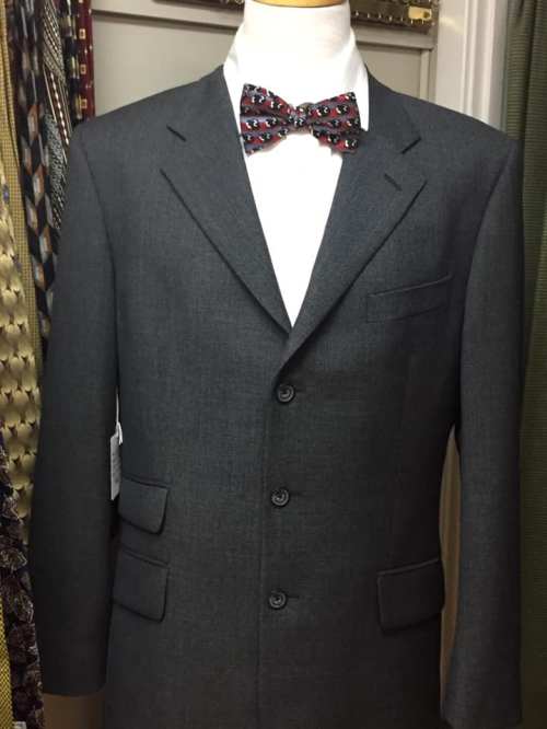 A gray suit jacket displayed on a mannequin, paired with a patterned bow tie.
