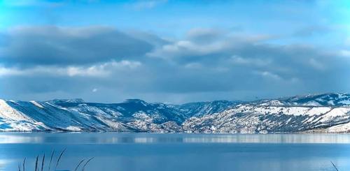 A serene lake surrounded by snow-capped mountains under a blue sky with fluffy clouds.