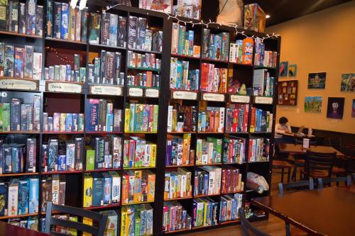 A colorful bookshelf filled with various board games in a cozy café setting.