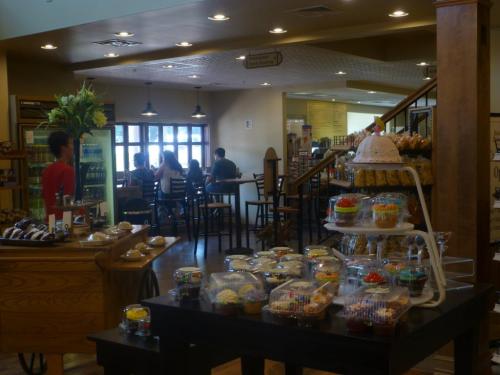A cozy café interior with a display of colorful desserts in the foreground and customers seated in the background.