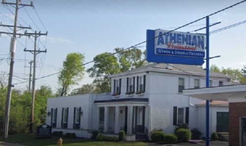 Athenian Restaurant building with a sign, surrounded by trees and power lines on a clear day.