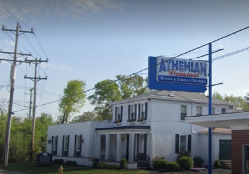 Athenian Restaurant building with a sign, surrounded by trees and power lines.