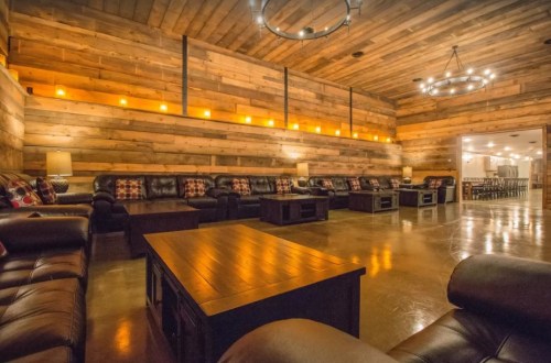 Cozy lounge with wooden walls, leather seating, and warm lighting, featuring a central coffee table.