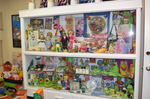 A display case filled with various Kermit the Frog collectibles, toys, and memorabilia from the Muppets.