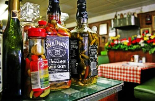 Bottles of Jack Daniel's whiskey and pickled vegetables on a table in a cozy diner setting.