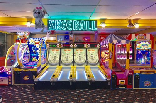 Colorful arcade with skeeball machines, plush toys, and various games under bright lights. Fun atmosphere for all ages.