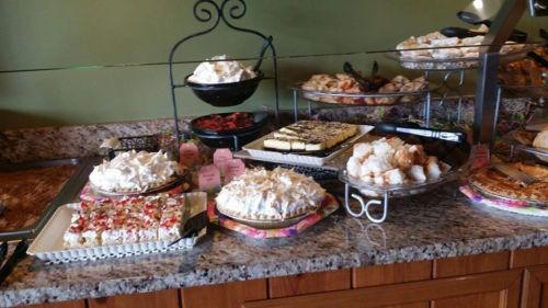 A display of various desserts, including cakes, pastries, and meringue, on a granite countertop.