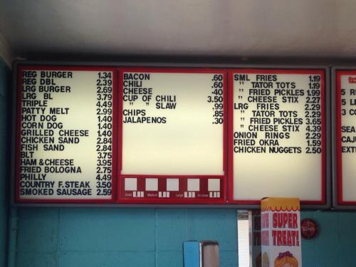Menu board displaying various food items and prices, including burgers, hot dogs, and sides.