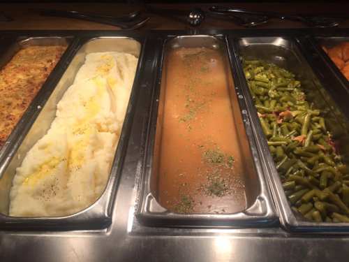 A buffet tray featuring mashed potatoes, gravy, and green beans.