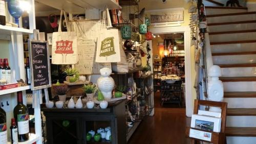 A cozy shop interior featuring shelves of products, bags hanging, and a staircase leading to the upper level.