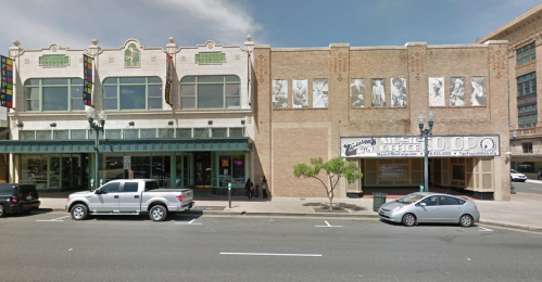 Historic buildings with large windows and murals, featuring a music office sign, along a city street.