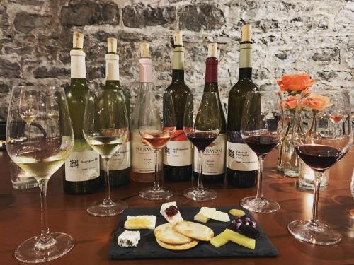 A selection of wine bottles and glasses with various wines, accompanied by a cheese platter on a wooden table.