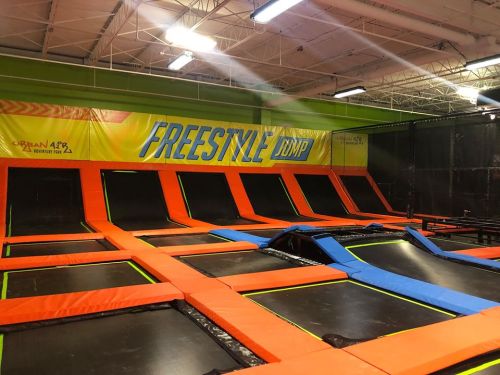 Indoor trampoline park featuring multiple trampolines in vibrant colors, labeled "Freestyle Jump."