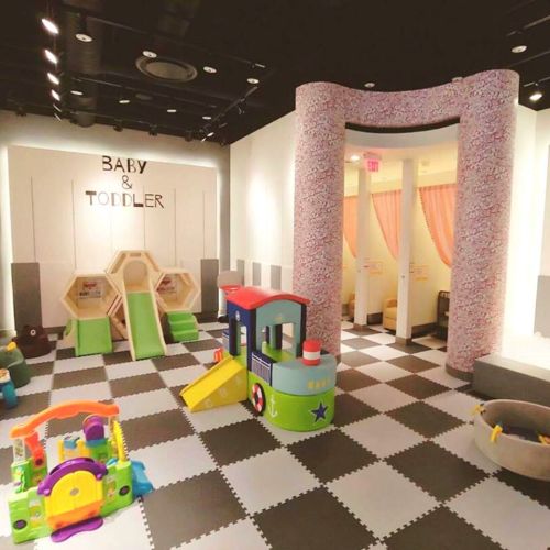 A colorful play area for babies and toddlers featuring soft play structures, toys, and a cozy seating area.