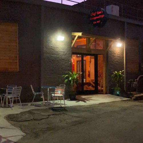 Exterior of Chef Tan's Underground Café at dusk, featuring a welcoming entrance and outdoor seating.