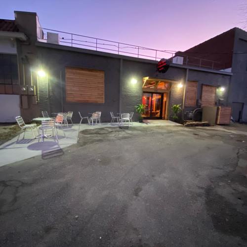A dimly lit outdoor seating area with metal chairs in front of a modern building at dusk.