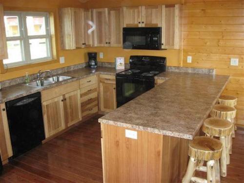 A cozy kitchen with wooden cabinets, a countertop, and three wooden stools, featuring modern appliances and warm colors.