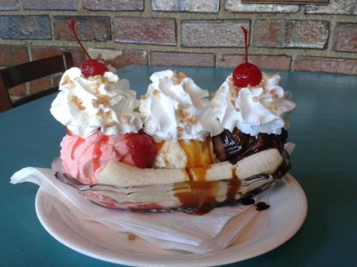 A banana split with scoops of strawberry, vanilla, and chocolate ice cream, topped with whipped cream, nuts, and cherries.