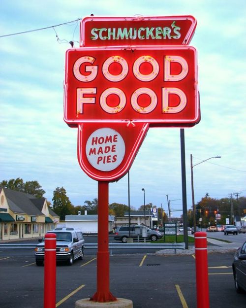 Neon sign for Schmucker's Good Food featuring "Home Made Pies" in a retro style, set in a parking lot.