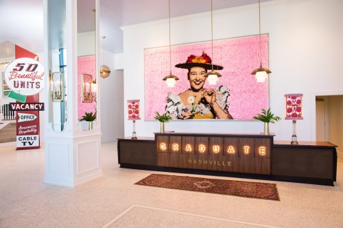 A stylish hotel lobby with a large pink artwork, a reception desk, and vintage signage in Nashville.