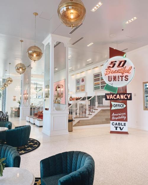 Bright, modern lobby with stylish seating, decorative lighting, and a large neon sign indicating "50 Beautiful Units" and "Vacancy."