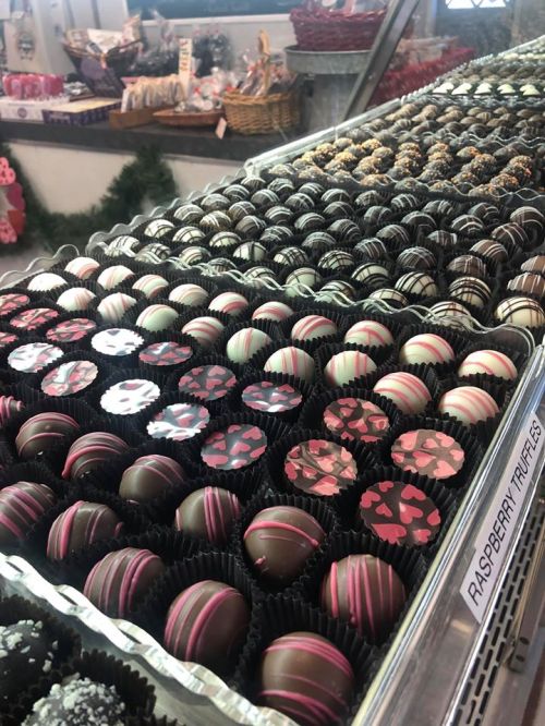 A display of assorted chocolate truffles in various designs and colors, arranged neatly in trays.
