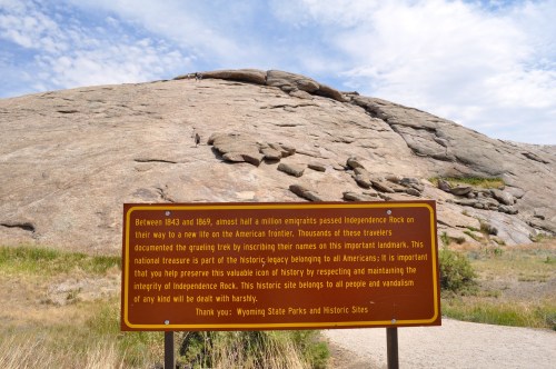 Sign at Independence Rock, detailing its historical significance for emigrants on the American frontier. Rocky landscape in background.