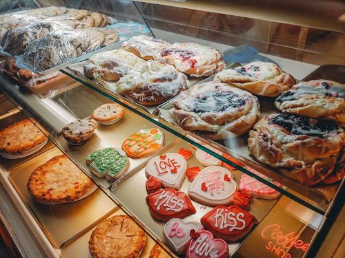 A display case filled with various baked goods, including cookies, pastries, and decorated cookies.