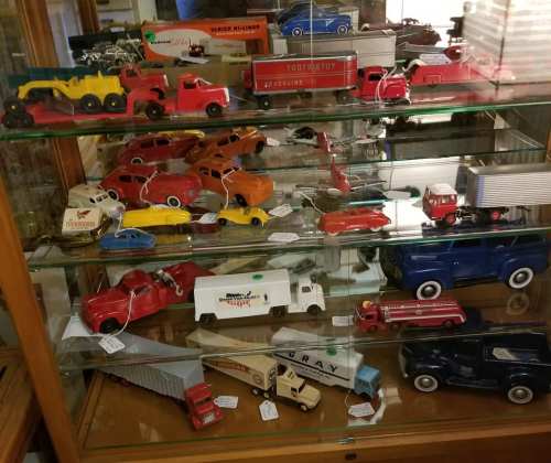 A display case filled with various vintage toy cars and trucks in different colors and styles.