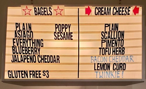 Menu board displaying bagel and cream cheese options, including flavors like plain, everything, and scallion.