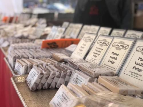 A display of various fudge flavors in a market, with labeled packages arranged neatly on a table.