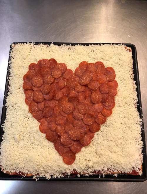 A rectangular pizza topped with a heart-shaped arrangement of pepperoni slices on a bed of cheese.