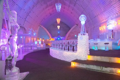 A colorful ice bar with illuminated sculptures, chandeliers, and a frosty interior, creating a magical atmosphere.