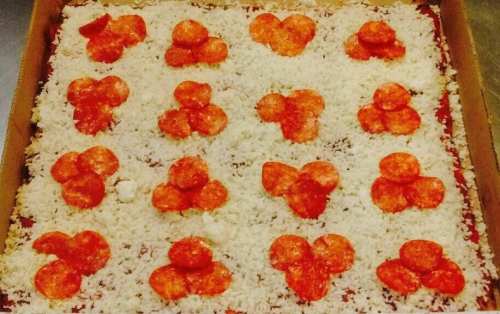 A pizza topped with pepperoni slices and a generous layer of shredded cheese on a red sauce base.