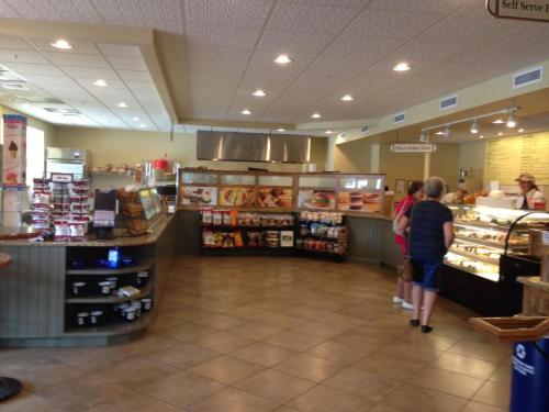 A cozy café interior with a display of baked goods, snacks, and customers ordering at the counter.