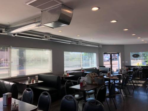 Interior of a modern diner with black booths, tables, and large windows, featuring a clean and bright atmosphere.