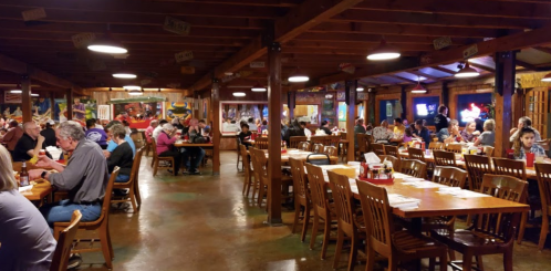 A bustling restaurant interior with wooden tables, diners enjoying meals, and colorful wall art.